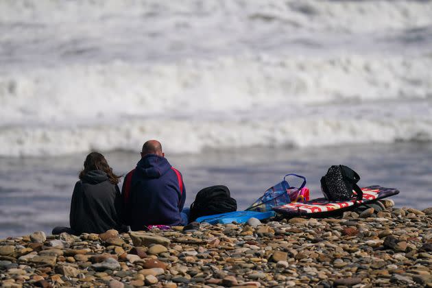 Two people sit on the pebbles on Saltburn beach on August 09, 2023 in Saltburn-By-The-Sea, England.