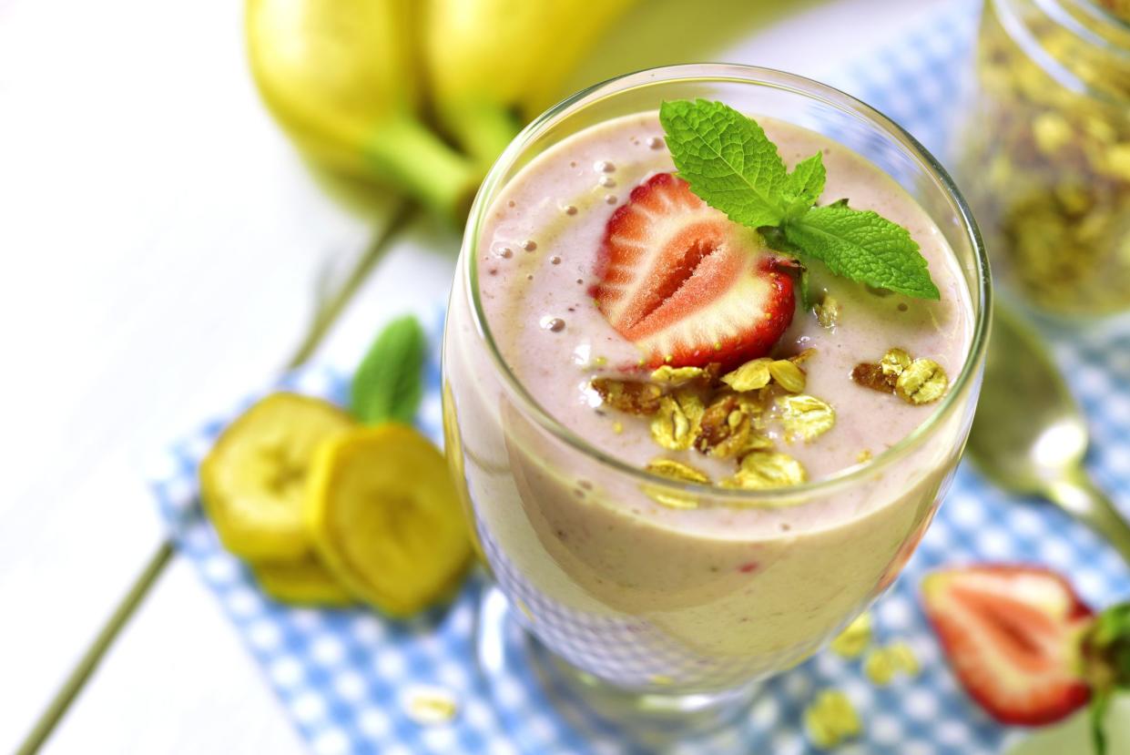 Banana smoothie with strawberry and oat in a glass on a white background.