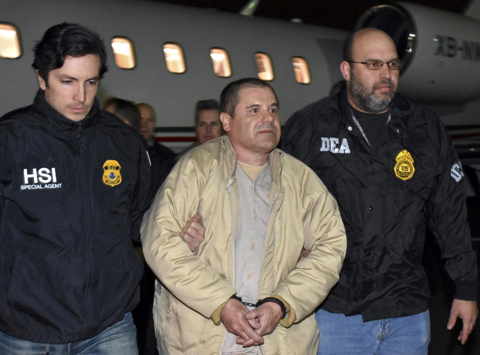 FILE - In this Jan. 19, 2017 file photo provided U.S. law enforcement, authorities escort Mexican drug lord Joaquin "El Chapo" Guzman, center, from a plane in Ronkonkoma, N.Y.  Each time Guzman appears in court in his U.S. case, authorities transporting him to and from jail shut down the Brooklyn Bridge to make way for a police motorcade that includes a SWAT team and an ambulance, all tracked by helicopters.  At a pretrial hearing, Tuesday, June 26, 2018, U.S. District Judge Brian Cogan said he was still considering the change of venue that prosecutors say isn't necessary. He also has yet to rule on a demand by Guzman's lawyers that the government turn over evidence that could help his defense. (U.S. law enforcement via AP, File)