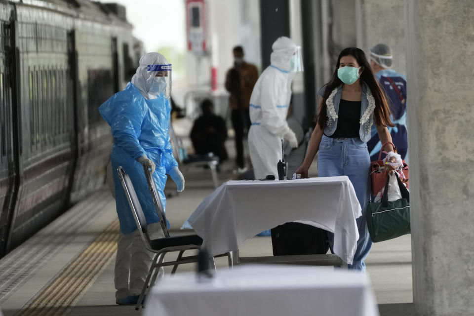 A COVID-19 patient, front right, prepares to get into a train at Rangsit train station in Pathum Thani Province, Thailand, to head to her hometown Tuesday, July 27, 2021. Thai authorities began transporting some people who have tested positive with the coronavirus from Bangkok to their hometowns on Tuesday for isolation and treatment, to alleviate the burden on the capital’s overwhelmed medical system. (AP Photo/Sakchai Lalit)