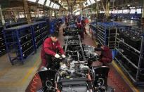 Workers install the chassis along a production line at a truck factory of Anhui Jianghuai Automobile Co. Ltd (JAC Motors) in Hefei, Anhui province May 5, 2014. REUTERS/Stringer