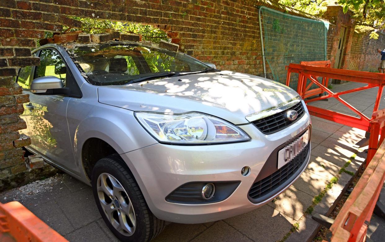 Eye-witnesses revealed an elderly male driver tried to parallel park the automatic silver Ford Focus Sport for his wife – but managed to reverse it through the wall, causing a 'huge bang'