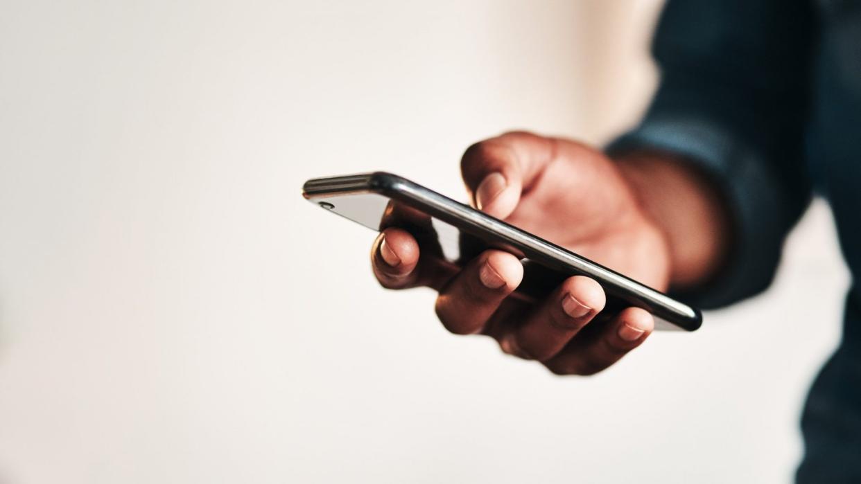 Cropped shot of an unrecognizable businessman standing alone in his home office and texting on his cellphone.