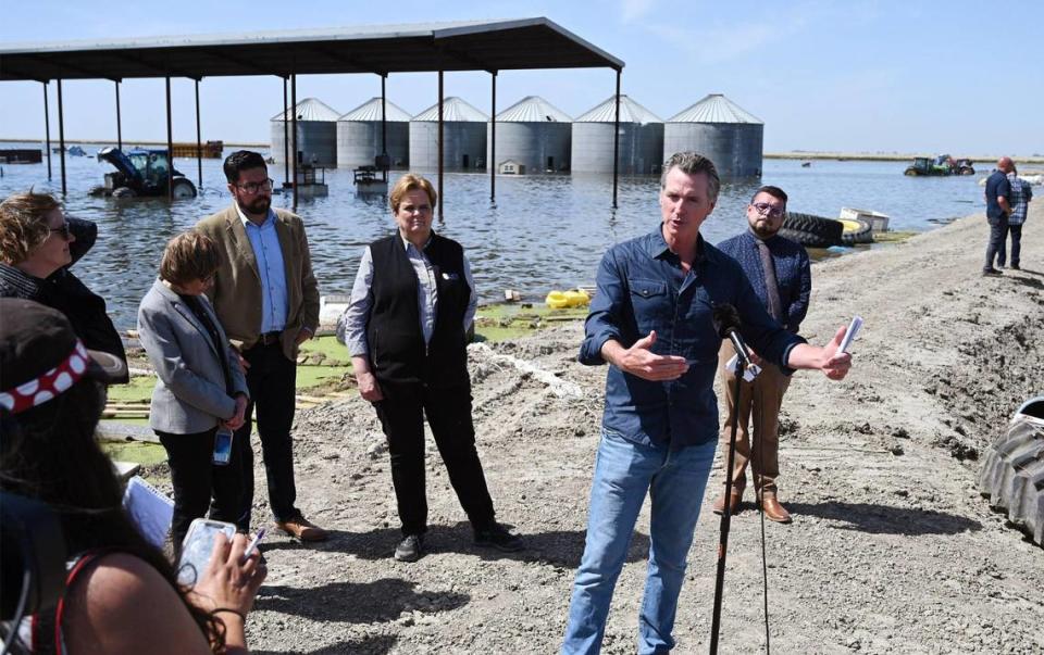 California Governor Gavin Newsom, second from right, speaks to the media at Hansen Ranches in an area surrounded by flooded land along 6th Avenue Tuesday afternoon, April 25, 2023 just south of Corcoran, CA.