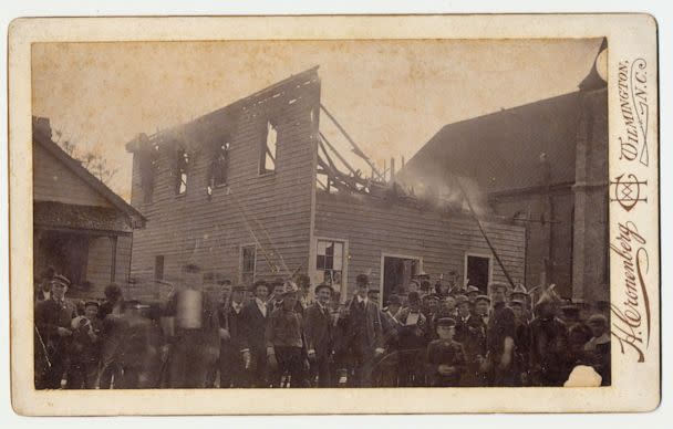 PHOTO: Men stand in front of The Daily Record, the only Black newspaper, after burning it to the ground (Courtesy of New Hanover County Public Library, North Carolina Room.)