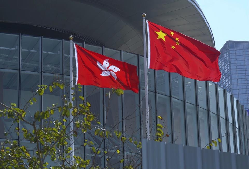 FILE - In this April 13, 2021, file photo, China's national flag, right, and Hong Kong's flag flutter at the Legislative Council in Hong Kong. Hong Kong's polls for an election committee that will vote for the city's leader kicked off Sunday amid heavy police presence, with chief executive Carrie Lam saying that it is "very meaningful" as it is the first election to take place following electoral reforms. (AP Photo/Vincent Yu, File)