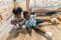 Jazzmyn, left, and Zavion Guzman play with Zavion's toys Thursday, Sept. 17, 2020, in Newark, N.J. Four-year-old Zavion and 2-year-old Jazzmyn have been taken in by the oldest of Lunisol Guzman's other three children, Katherine and Jennifer, after she died from symptoms of coronavirus. Lunisol Guzman had adopted them when she was in her 40s. (AP Photo/Mary Altaffer)