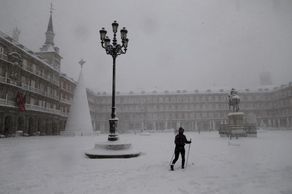 A woman skis while crossing the Plaza Mayor in Madrid during a heavy snowfall in Madrid, Spain, Saturday, Jan. 9, 2021. An unusual and persistent blizzard has blanketed large parts of Spain with snow, freezing traffic and leaving thousands trapped in cars or in train stations and airports that had suspended all services as the snow kept falling on Saturday. The capital, Madrid, and other parts of central Spain activated for the first time its red weather alert, its highest, and called in the military to rescue people from cars vehicles trapped in everything from small roads to the city's major thoroughfares. (AP Photo/Andrea Comas)