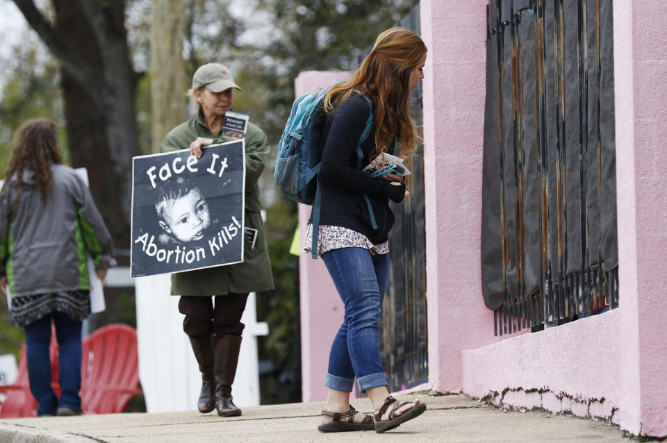 FILE - In this March 20, 2018, file photo, anti-abortion sidewalk counselors call out to a woman entering the Jackson Women's Health Organization's clinic, the only facility in the state that performs abortions, in Jackson, Miss. A new Mississippi law could make it nearly impossible for most pregnant women to get an abortion there if it survives a court challenge. (AP Photo/Rogelio V. Solis, File)