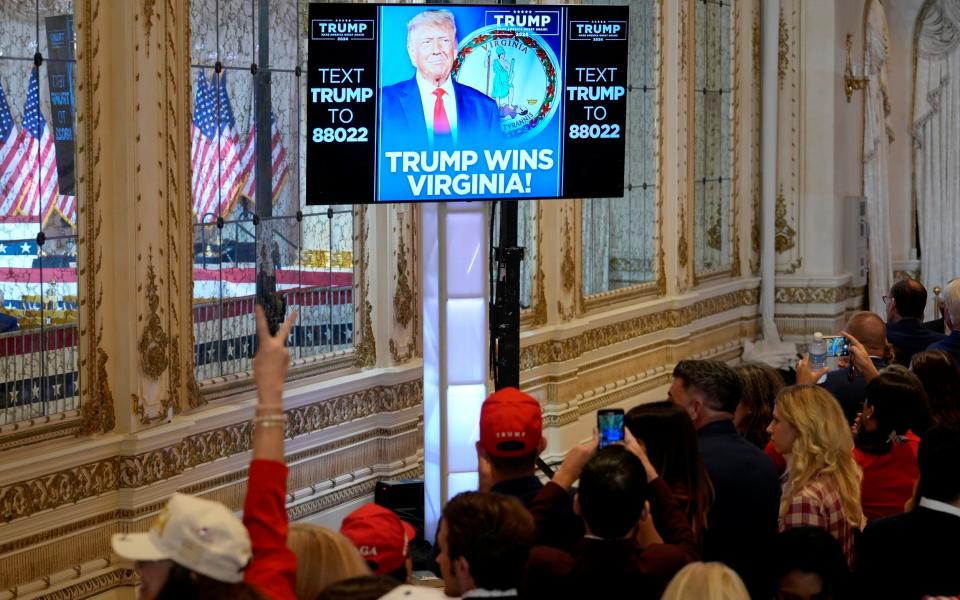 Supporters watch results on screen before Donald Trump speaks at a Super Tuesday election night party