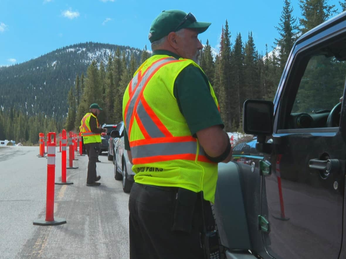 Alberta Parks employees survey drivers to see if they have purchased a park pass. No fines have been handed out so far, but the province plans to begin enforcement on those without a Kananaskis Conservation Pass. (Helen Pike/CBC - image credit)