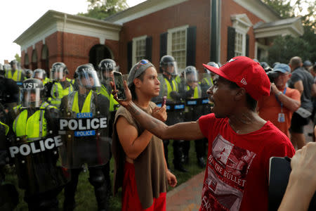 FILE PHOTO: Protesters stand in front of Virginia State Police officers forming a cordon at the University of Virginia, ahead of the one year anniversary of the 2017 Charlottesville "Unite the Right" protests, in Charlottesville, Virginia, U.S., August 11, 2018. REUTERS/Lucas Jackson/File Photo