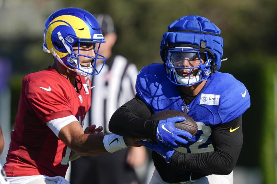 Rams quarterback Jimmy Garoppolo hands Blake Corum the football during camp practice on Monday.