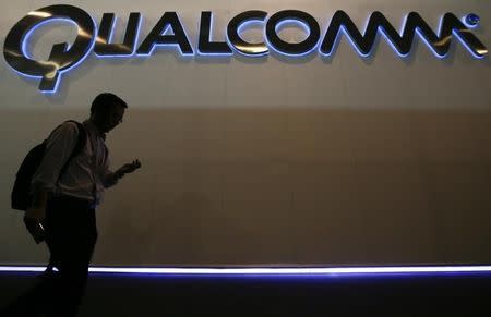 A man walks past Qualcomm stand while attending the Mobile World Congress in Barcelona March 3, 2015. REUTERS/Albert Gea