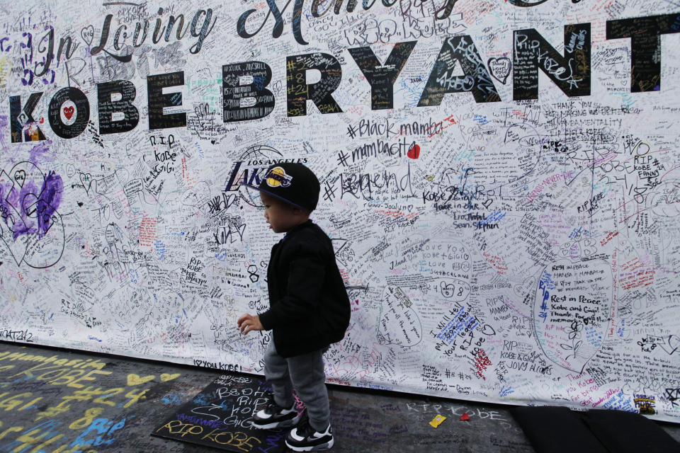 A boy walks by a standing board with messages for the late Kobe Bryant at a memorial for Bryant in front of Staples Center in Los Angeles Sunday, Feb. 2, 2020. Bryant, the 18-time NBA All-Star who won five championships and became one of the greatest basketball players of his generation during a 20-year career with the Lakers, died in a helicopter crash Sunday, Jan. 26. (AP Photo/Damian Dovarganes)
