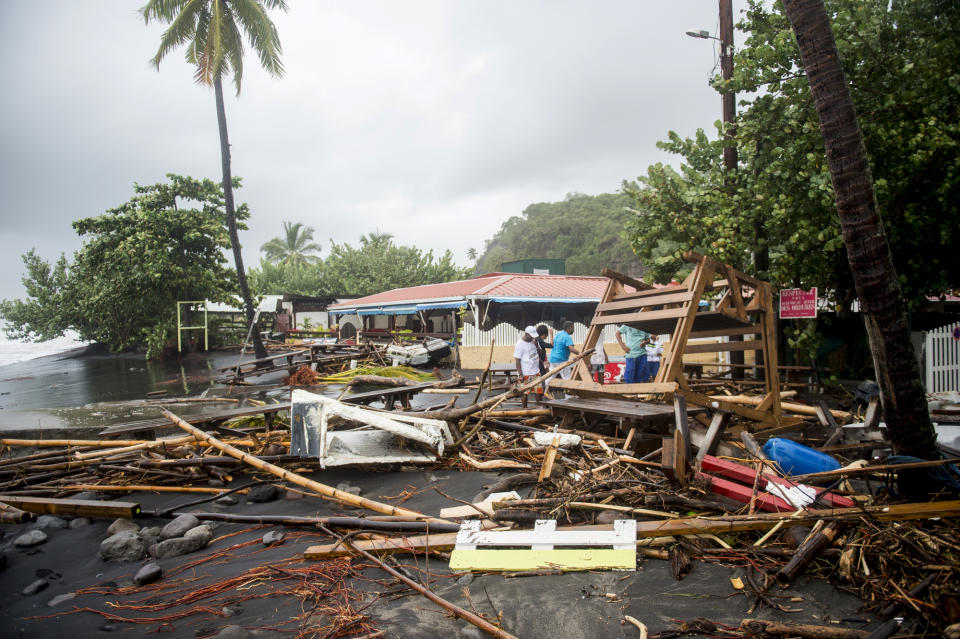 <p>People stand next to debris at a restaurant in Le Carbet, on the French Caribbean island of Martinique, after it was hit by Hurricane Maria, on Sept. 19, 2017. (Photo: Lionel Chamoiseau/AFP/Getty Images) </p>