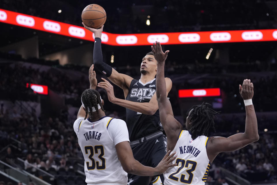 San Antonio Spurs center Victor Wembanyama, top, shoots over Indiana Pacers center Myles Turner (33) and forward Aaron Nesmith (23) during the first half of an NBA basketball game in San Antonio, Sunday, March 3, 2024. (AP Photo/Eric Gay)