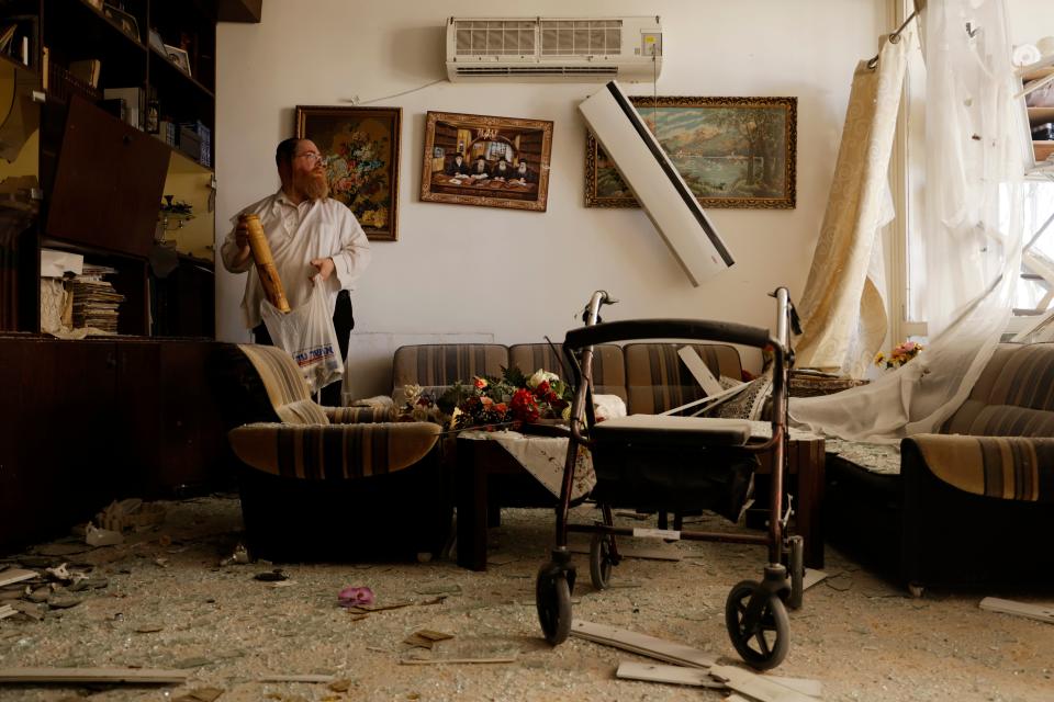 Crooked picture frames hang on the wall as an Israeli gathers his belongings in a carrier bag following a Hezbollah rocket attack near Haifa (Getty Images)