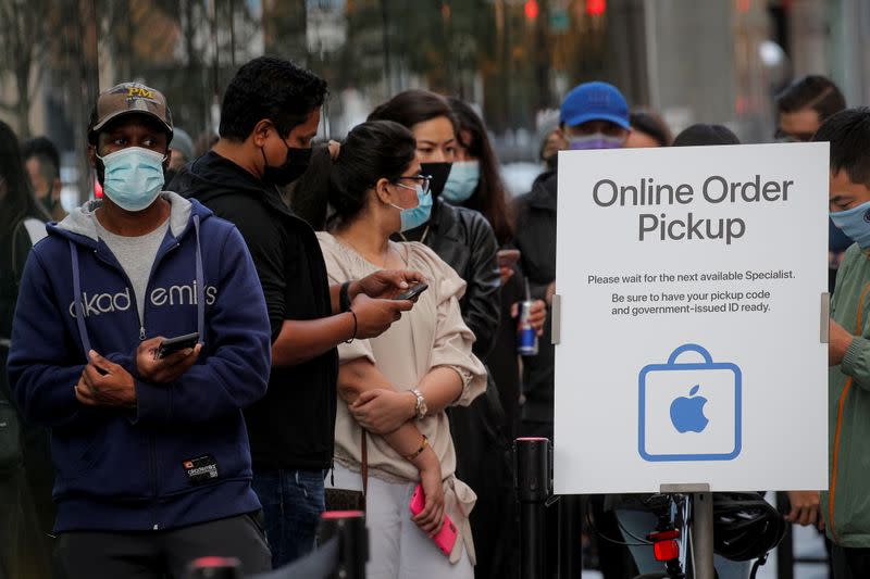 Customers wait in line outside an Apple Store to pick up Apple's new 5G iPhone 12 in Brooklyn, New York