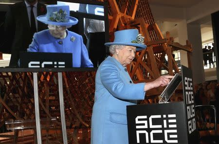 Britain's Queen Elizabeth presses a button to send her first Tweet during a visit to the 'Information Age' Exhibition at the Science Museum, in London October 24, 2014. REUTERS/Chris Jackson/Pool