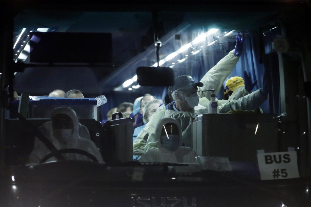 Passengers disembarked from the quarantined Diamond Princess cruise ship, wave from the bus as they leave the port: AP