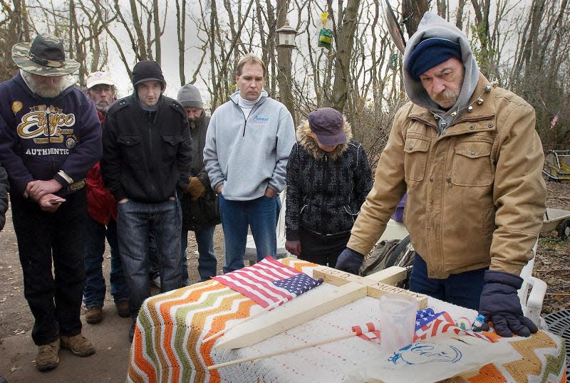 Butch Huffman,right and family and friends of Leo Murphy gather Tuesday for a memorial service held for Murphy at the homeless camp in Bristol Township where he lived before dying of a heart attack in September 2010