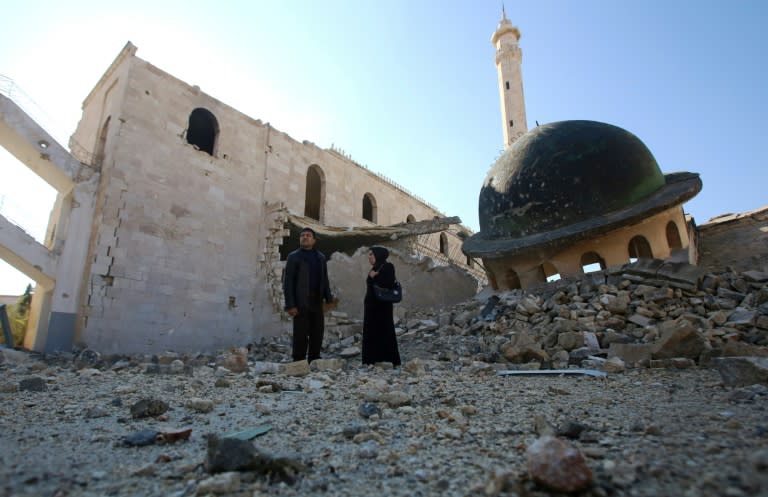 Kefa Jawish (right) and husband Tajeddin Ahmed walk near a destroyed mosque in Aleppo's Hanano district as they head to check their house for the first time in four years in Haydariya neighbourhood on December 4, 2016