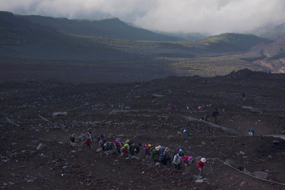 In this Aug. 11, 2013 photo, hikers climb one of the trails on Mount Fuji. The recent recognition of the 3,776-meter (12,388-foot) peak as a UNESCO World Heritage site has many here worried that will draw still more people, adding to the wear and tear on the environment from the more than 300,000 who already climb the mountain each year. (AP Photo/David Guttenfelder)