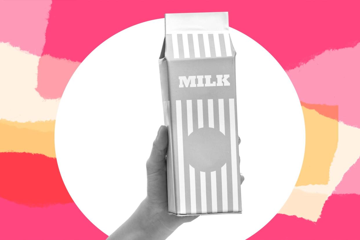A hand holds up a carton of milk.