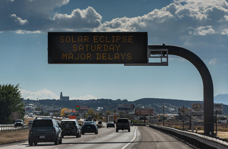 a line of cars stopped on a highway under a sign that reads 