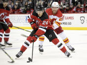 New Jersey Devils defenseman Ty Smith (24) skates with the puck as he is pursued by Calgary Flames center Blake Coleman (20) during the first period of an NHL hockey game Tuesday, Oct. 26, 2021, in Newark, N.J. (AP Photo/Bill Kostroun)