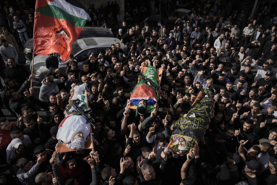 Mourners carry the bodies of Asaad Al-Dam, right, Mahmoud Abu Al-Hayja, center, and Ammar Abu Al-Wafa, draped in the Islamic Jihad militant group and Hamas flags, during their funeral in the Jenin refugee camp, West Bank, Sunday, Nov. 26, 2023. Israeli forces operating in the occupied West Bank killed at least eight Palestinians in a 24-hour period, Palestinian health officials said Sunday. (AP Photo/Majdi Mohammed)