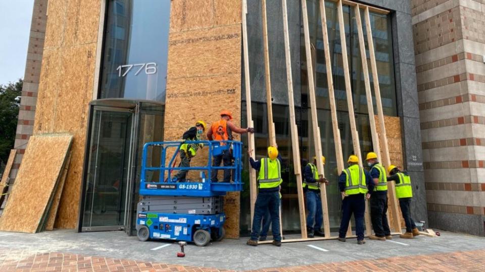 Protections get installed on building facades Sunday near the White House as building managers and local businesses fear violent demonstrations ahead of the Nov. 3 presidential election. (Photo by Daniel Slim/AFP via Getty Images)