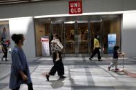 People wearing face masks walk past a Uniqlo store in Beijing