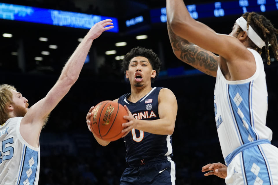 Virginia's Kihei Clark (0) looks to pass against North Carolina's Brady Manek (45) in the first half of an NCAA college basketball game during quarterfinals of the Atlantic Coast Conference men's tournament, Thursday, March 10, 2022, in New York. (AP Photo/John Minchillo)