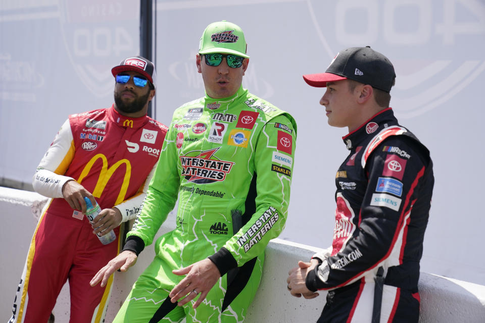Kyle Busch, center, talks with Bubba Wallace, left, and Christopher Bell before player introductions at the NASCAR Cup Series auto race at Michigan International Speedway, Sunday, Aug. 22, 2021, in Brooklyn, Mich. (AP Photo/Carlos Osorio)