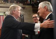 US President Donald J. Trump greets Secretary of the Treasury Steve Mnuchin (C) and Secretary of State Rex Tillerson (R) on his way out after delivering his first address to a joint session of Congress in Washington, DC February, 28 2017