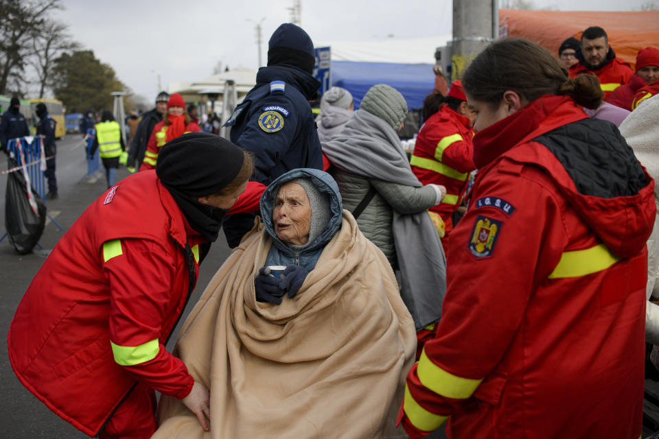 Emergency Situations Department employees talk to wheelchair user Katia, 90 years-old, a refugee fleeing the conflict from neighbouring Ukraine at the Romanian-Ukrainian border, in Siret, Romania, Saturday, March 5, 2022. (AP Photo/Andreea Alexandru)