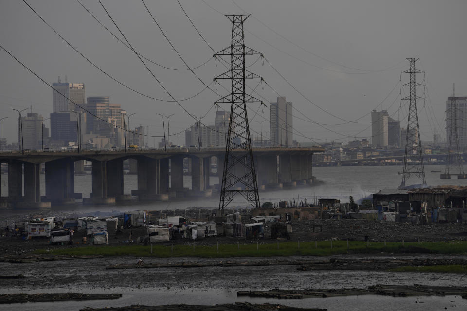 FILE - High tension power lines pass through Makoko slum in Lagos, Nigeria, Saturday, Aug. 20, 2022. From Zimbabwe, where many must work at night because i t's the only time there is power, to Nigeria where collapses of the grid are frequent, the reliable supply of electricity remains elusive across Africa. (AP Photo/Sunday Alamba/File)