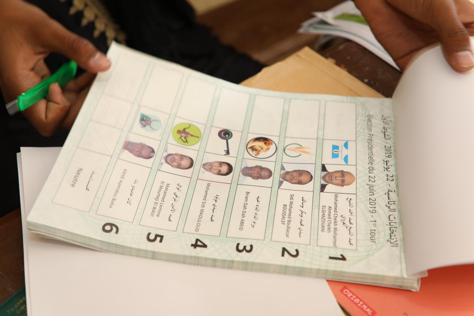 An election officials holds a ballot paper at a polling station in Nouakchott, Mauritania, Saturday June 22, 2019. Mauritanians are choosing between outgoing President Mohamed Ould Abdel Aziz's heir apparent former Defense Minister Mohamed ould El Ghazouani and five opposition candidates who believe the front-runner would represent a continuation of his rule in this West African country battling Islamic extremism. (AP Photo/Elhady Ould Mohamedou)