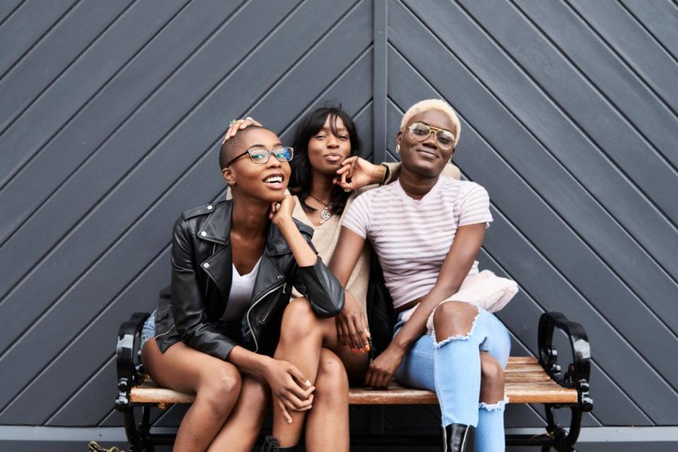 Three friends pose on a bench together