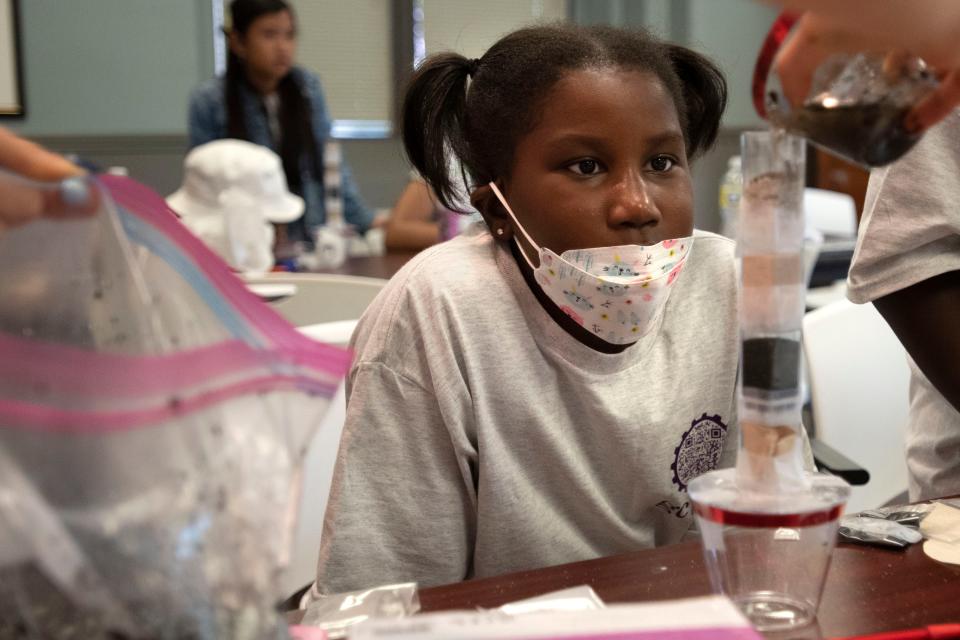 Girls Code the World summer camp student Dior looks at her water filter experiment as the instructor pours dirty water at the Academy of Natural Sciences in Philadelphia on Thursday, June 30, 2022.