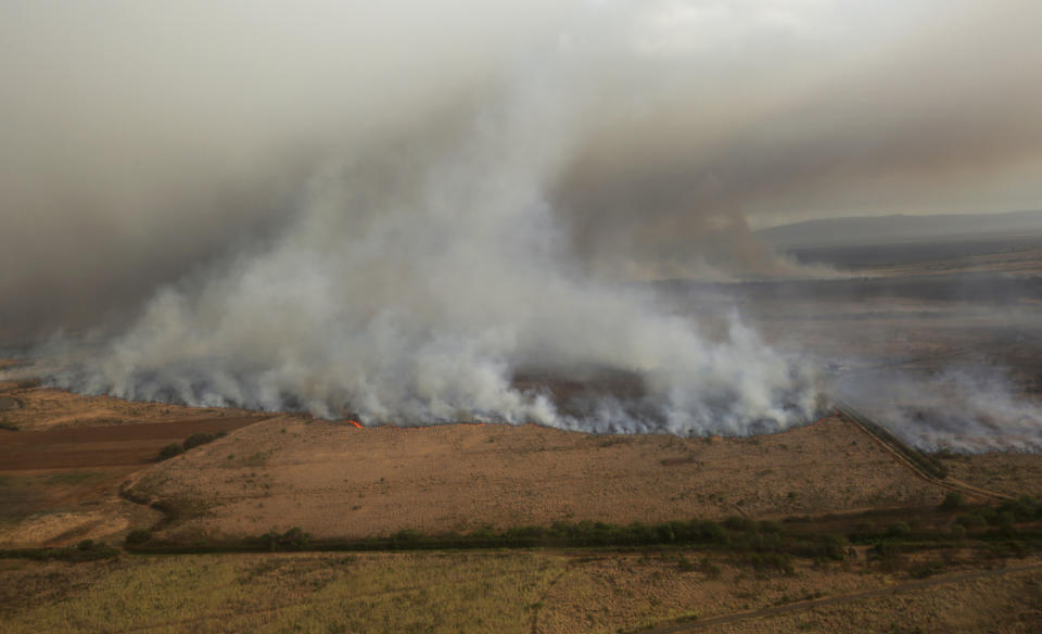 This Thursday, July 11, 2019 photo provided by the County of Maui shows a brush fire that has prompted evacuation orders and diverted flights on the island of Maui in Hawaii. Maui Fire Department officials said hot, dry and windy conditions Friday could worsen the fire. The National Guard is helping firefighters and conducting water drops with a helicopter. The blaze fueled by dry brush and strong winds erupted Thursday on northwestern side of the island, burning 14 square miles (36 square kilometers) of fields. (Chris Sugidono/County of Maui via AP)