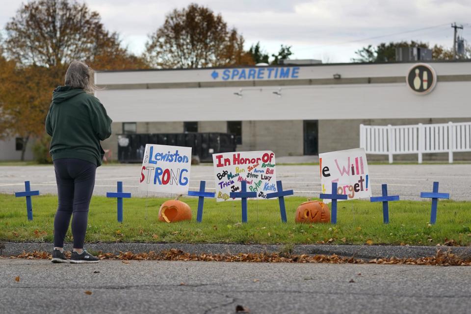 A woman visits a makeshift memorial outside Sparetime Bowling Alley, the site of one of this week's mass shootings, Saturday, Oct. 28, 2023, in Lewiston, Maine. A gunman killed multiple people at the bowling alley and a bar in Lewiston on Wednesday. The bowling alley was renamed in 2021 to Just-In-Time Recreation. (AP Photo/Robert F. Bukaty)