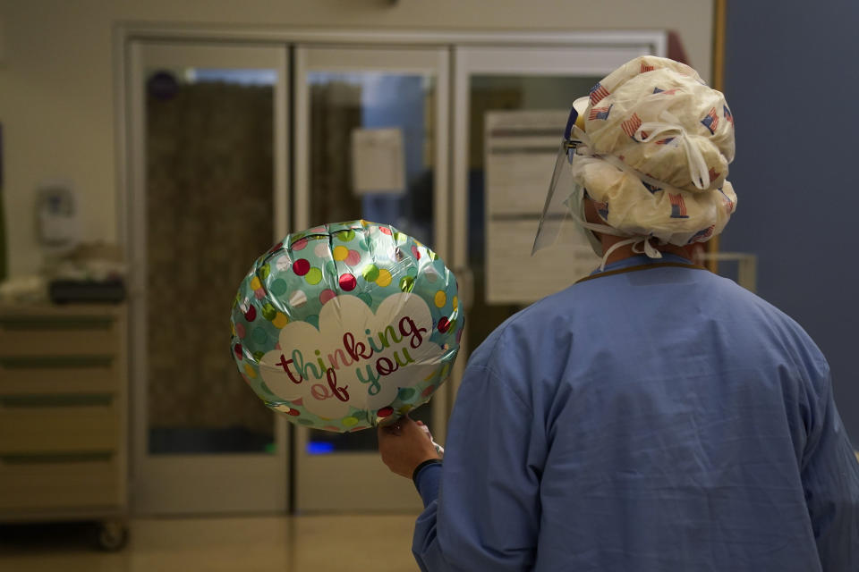 Registered nurse Anita Grohmann carries a balloon delivered to a patient in a COVID-19 unit at St. Joseph Hospital in Orange, Calif. Thursday, Jan. 7, 2021. The state's hospitals are trying to prepare for the possibility that they may have to ration care for lack of staff and beds — and hoping they don't have to make that choice as many hospitals strain under unprecedented caseloads. (AP Photo/Jae C. Hong)