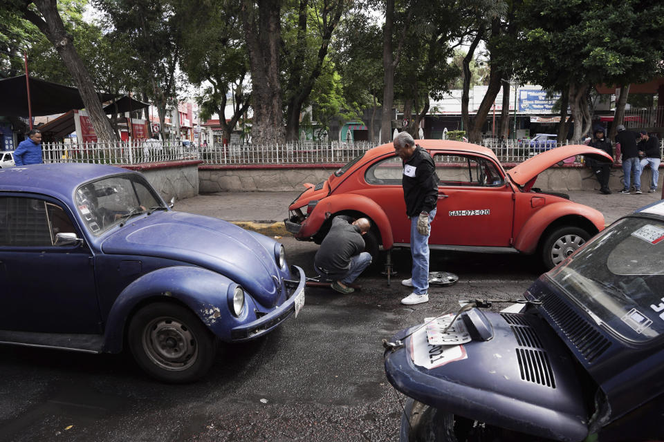 Taxistas que utilizan modelos Beetle de Volkswagen cambian una rueda pinchada en el vecindario de Cuautepec, en Ciudad de México, el viernes 21 de junio de 2024. Los mecánicos en la zona dicen que conducir un Beetle, o "vocho", como se los conoce en México, es una tradición en extinción porque las piezas han sido más difíciles de encontrar desde que Volkswagen detuvo la producción hace cinco años. (AP Foto/Aurea Del Rosario)