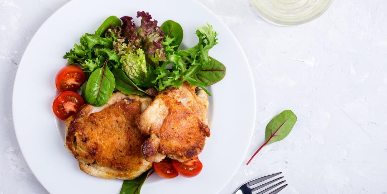 roast chicken legs on white plate over light gray plaster texture table