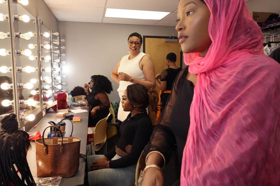 Director Tina Kelly, center, smiles as Michelle Washington, right, finishes getting ready for the dress rehearsal of “The Glorious World of Crowns, Kinks and Curls.” Kelly