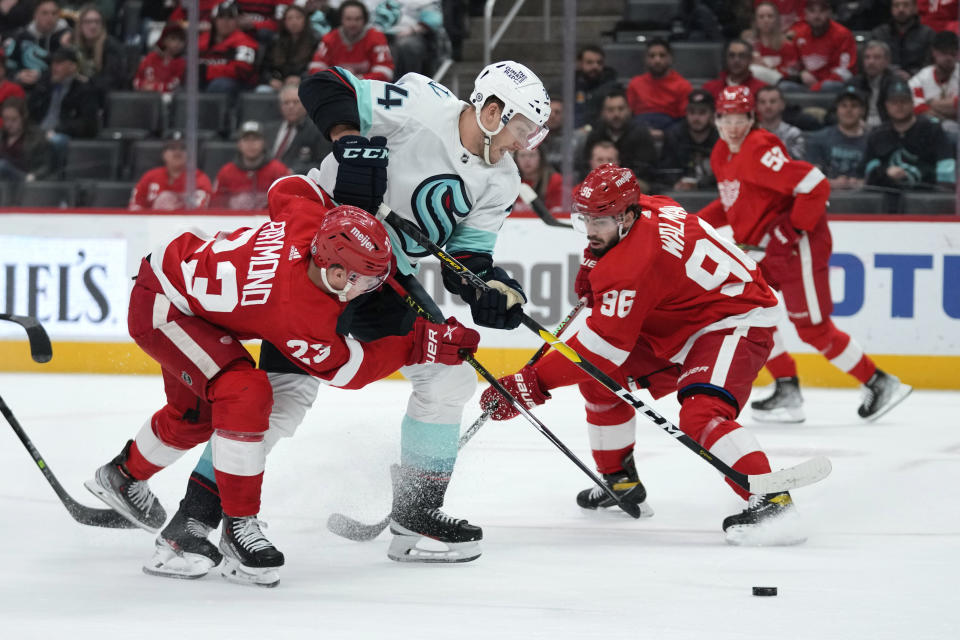 Seattle Kraken defenseman Jamie Oleksiak (24) breaks through Detroit Red Wings defenseman Jake Walman (96) and Detroit Red Wings left wing Lucas Raymond (23) in the first period of an NHL hockey game Thursday, March 2, 2023, in Detroit. (AP Photo/Paul Sancya)