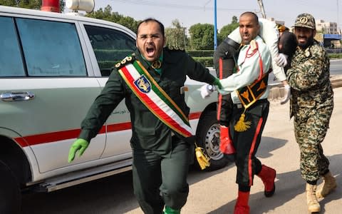 Iranian soldier carrying an injured comrade at the scene of an attack on a military parade in the southwestern city of Ahvaz - Credit: AFP